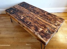 a wooden table sitting on top of a hard wood floor next to a white wall