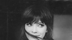 a black and white photo of a woman holding a toothbrush in her mouth while looking at the camera