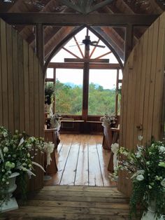 the inside of a church with wooden floors and flowers on each side of the door