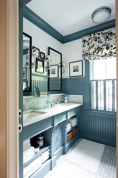 a bathroom with blue walls and white counter tops, along with pictures on the wall