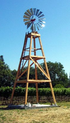 a wooden windmill sitting in the middle of a field