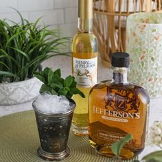 two bottles of liquor sitting on top of a table next to a glass filled with ice