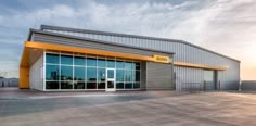 an empty parking lot in front of a building with large windows and yellow lettering on it