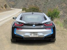 the bmw i8 is parked on the side of the road in front of a mountain