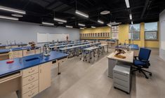 an empty classroom with blue desks and yellow walls