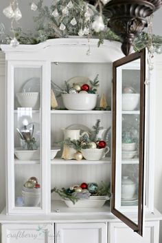 a white china cabinet with christmas decorations on top