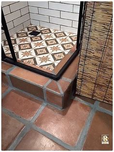 a tiled shower stall with a tile floor and wall in the corner, next to a metal cage