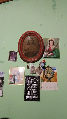 a green wall covered in pictures and other items on it's side with a clock