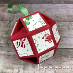 an origami christmas decoration hanging from a green ribbon on top of a wooden table