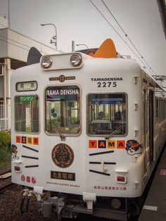 a white train on the tracks next to a building