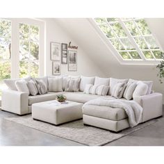 a living room with a large white sectional couch and footstool in front of an open window