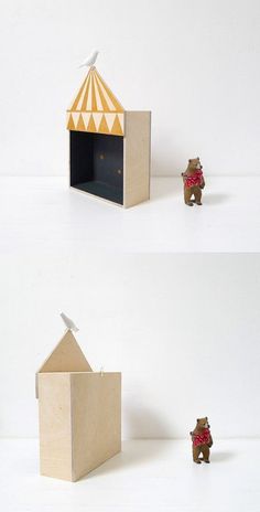 there is a small toy bear in front of a wooden box with a circus tent on it