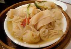 a wooden bowl filled with dumplings on top of a table