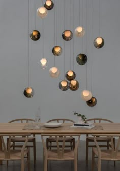 a dining room table and chairs with lights hanging from the ceiling