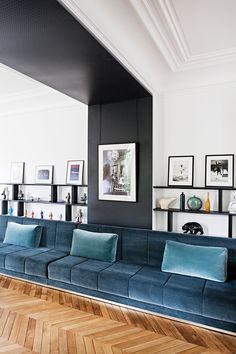 a living room with blue couches and pictures on the wall above them in black and white