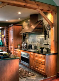 a large kitchen with wooden cabinets and black counter tops, along with stainless steel appliances