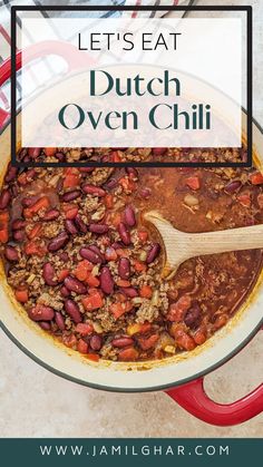 a pot filled with chili and beans on top of a counter next to a wooden spoon