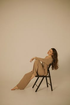 a woman sitting in a chair with her legs crossed and looking off to the side