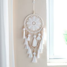 a white dream catcher hanging from the side of a wall next to a windowsill