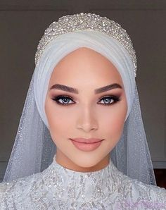 a woman wearing a white veil and headpiece with pearls on the top of her head