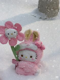 a hello kitty doll holding a flower in the snow