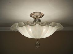 a white ceiling light hanging from the ceiling in a room with beige walls and flooring