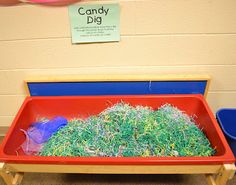 a red tray filled with grass next to blue bins