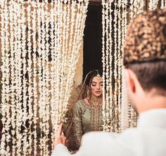 a man and woman standing next to each other in front of a curtain covered with beads