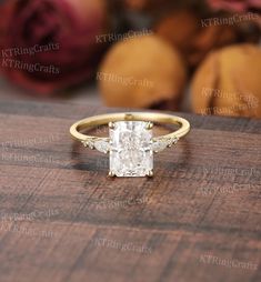 an engagement ring with a princess cut diamond surrounded by three small round diamonds on a wooden surface