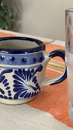 a blue and white bowl sitting on top of a table next to a glass filled with water