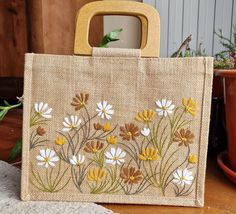 a bag with flowers painted on it sitting next to a potted plant