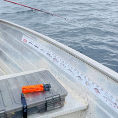 an orange and gray box sitting on top of a boat next to a fishing rod