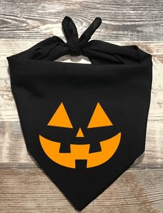 a black bandana with an orange pumpkin face on it