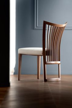 a wooden chair sitting on top of a hard wood floor next to a blue wall