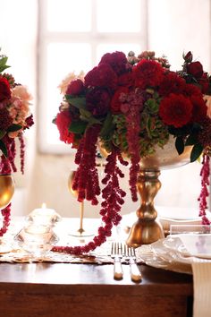 two vases filled with red flowers on top of a table next to each other