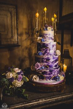 a wedding cake sitting on top of a table next to some flowers and candle lights