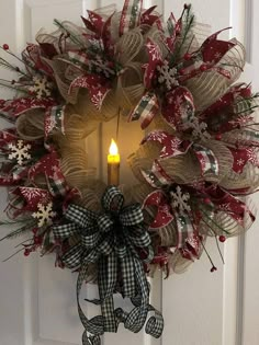 a christmas wreath with a lit candle hanging from the front door, decorated with burlocks and snowflakes