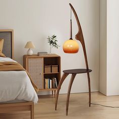 a bed room with a neatly made bed and a wooden floor lamp next to it