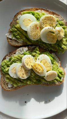 two halves of bread with avocado and hard boiled eggs on them sitting on a white plate