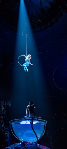 a man is suspended in the air on a rope above an audience at a circus