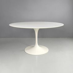 an oval white table sitting on top of a gray floor