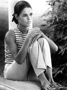 a black and white photo of a woman sitting on the ground with her arms folded