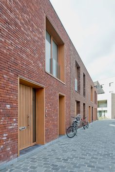 two bikes parked in front of a brick building with doors and windows on both sides