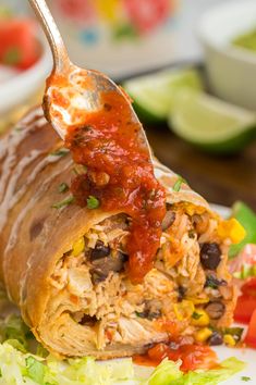 a close up of a burrito on a plate with a fork sticking out of it