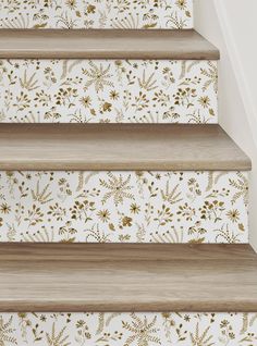 the stairs are painted with gold flowers and leaves on white wallpaper, along with wooden flooring