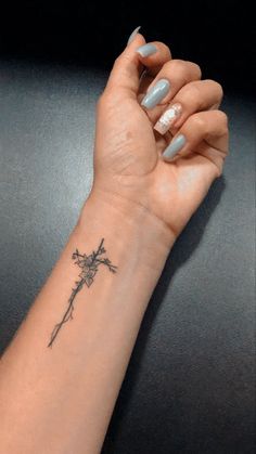 a woman's arm with a cross tattoo on it