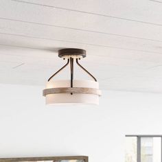 a light fixture hanging from the ceiling in a room with white walls and wood floors