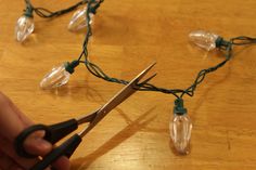 a pair of scissors cutting string lights on a table