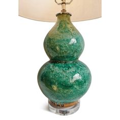 a green table lamp sitting on top of a white floor next to a light shade