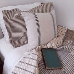 a bed with striped pillows and a book on top of it next to a night stand